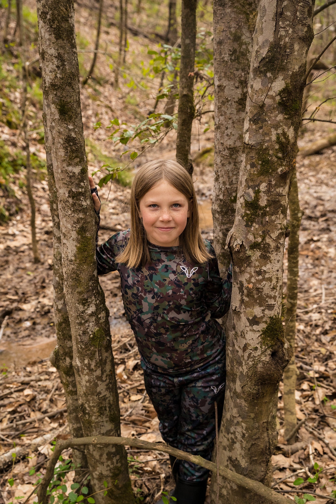 Girl in tree hunting wearing camo pants and camo shirt