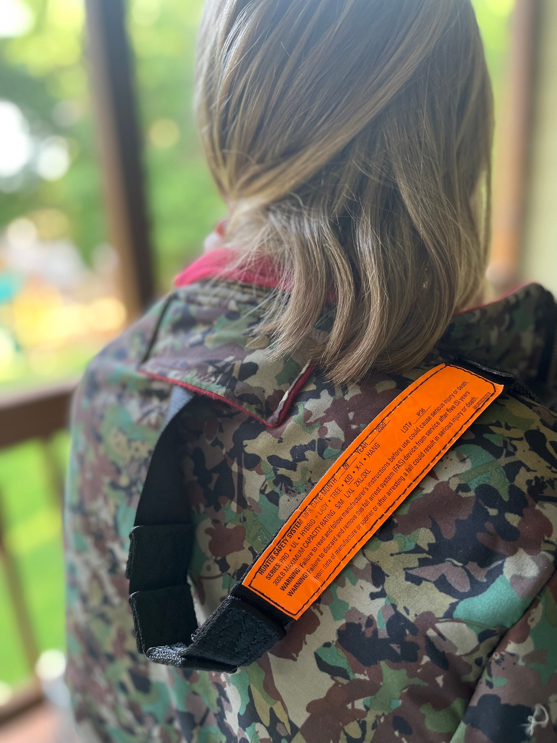 Girl wearing camo hunting jacket with harness pass through.