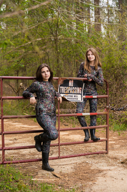 Two girls wearing camo standing at a gate